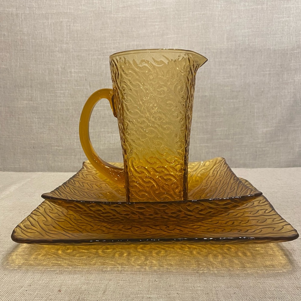 Matching amber glass two platters and pitcher. Link pattern.